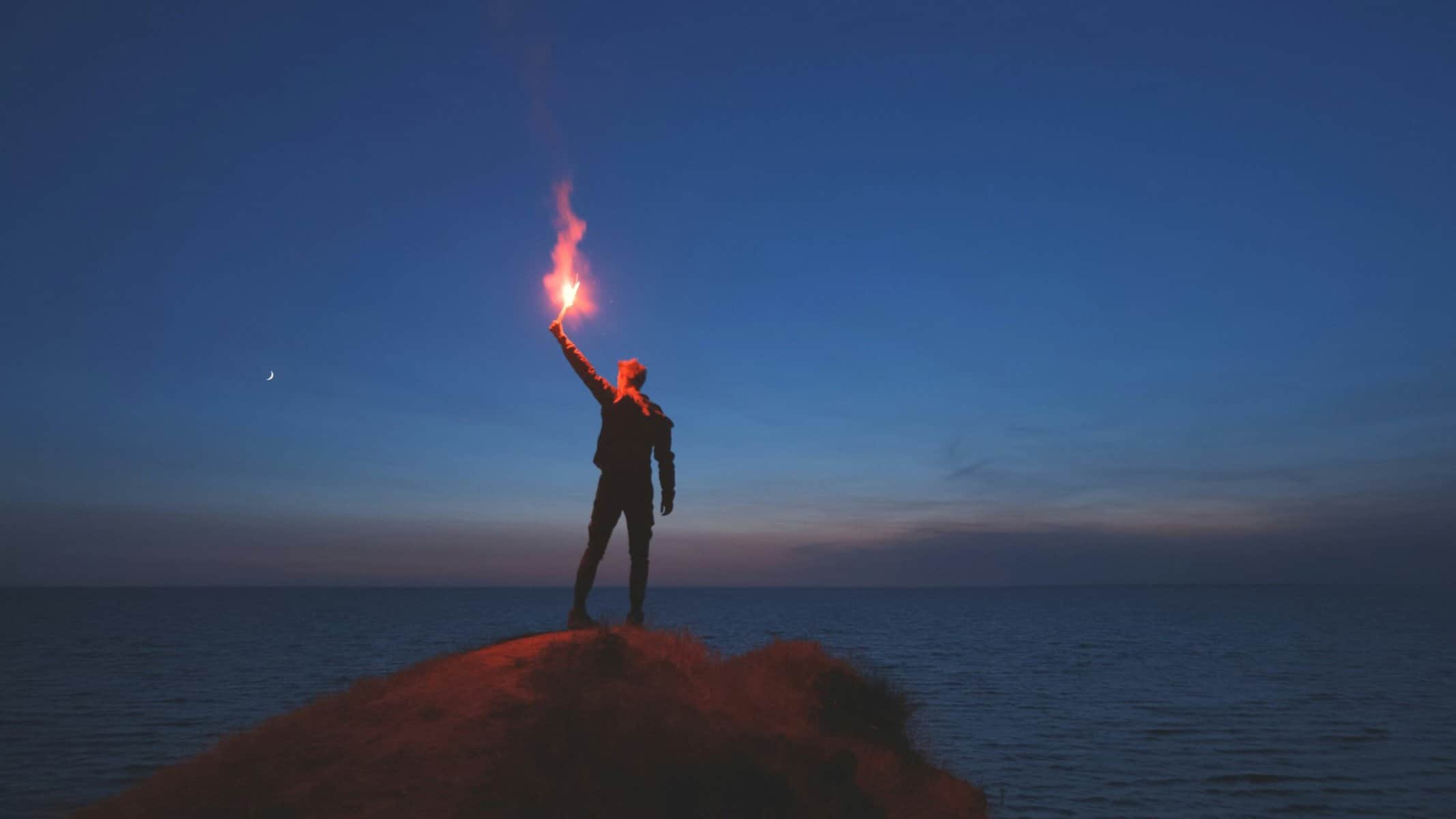 top salespeople on top of mountain holding torch at sunset