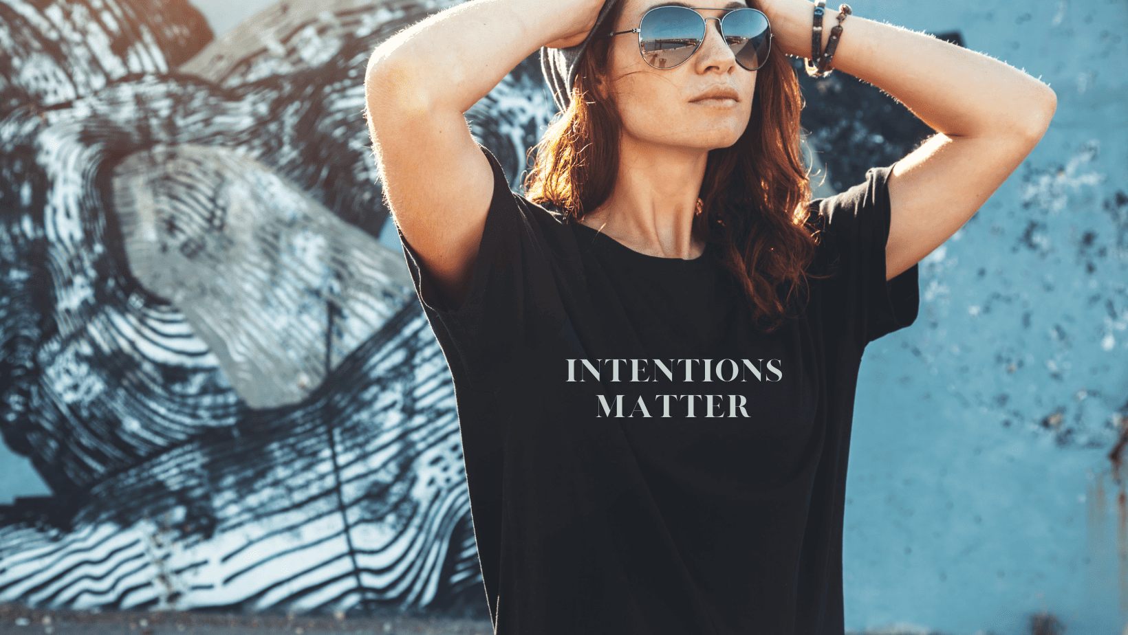 Blue background woman with hands on head black shirt saying intentions matter