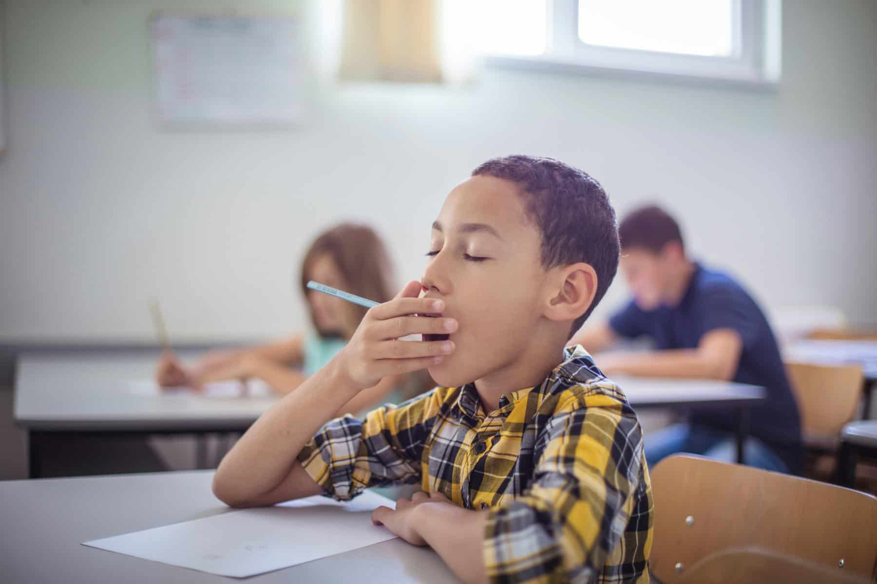 boy at school desk yawning