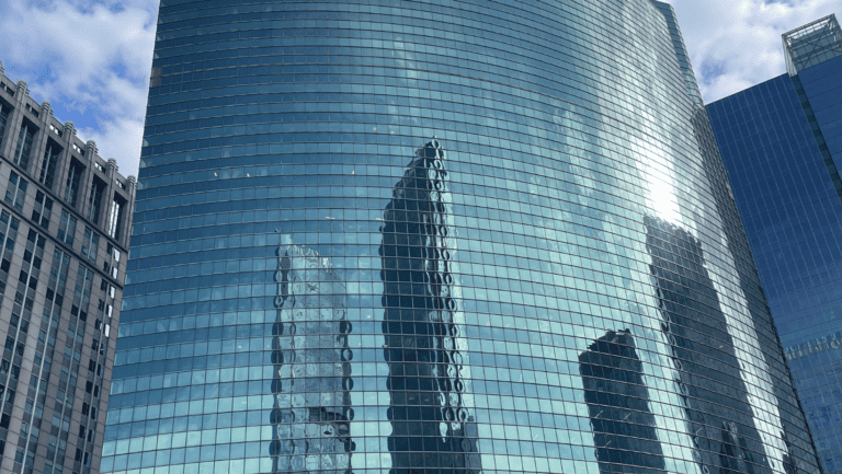 tall full window building with reflection of three buildings from across the street