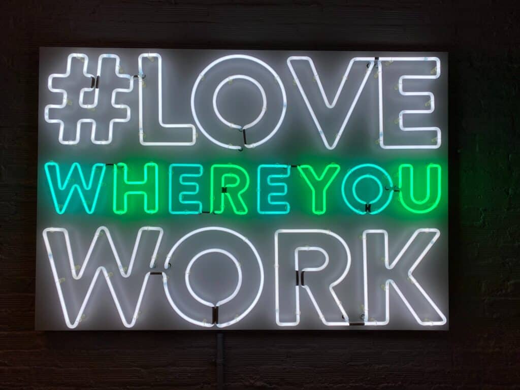 white and green neon sign saying hashtag love where you work as one sales leader tactics