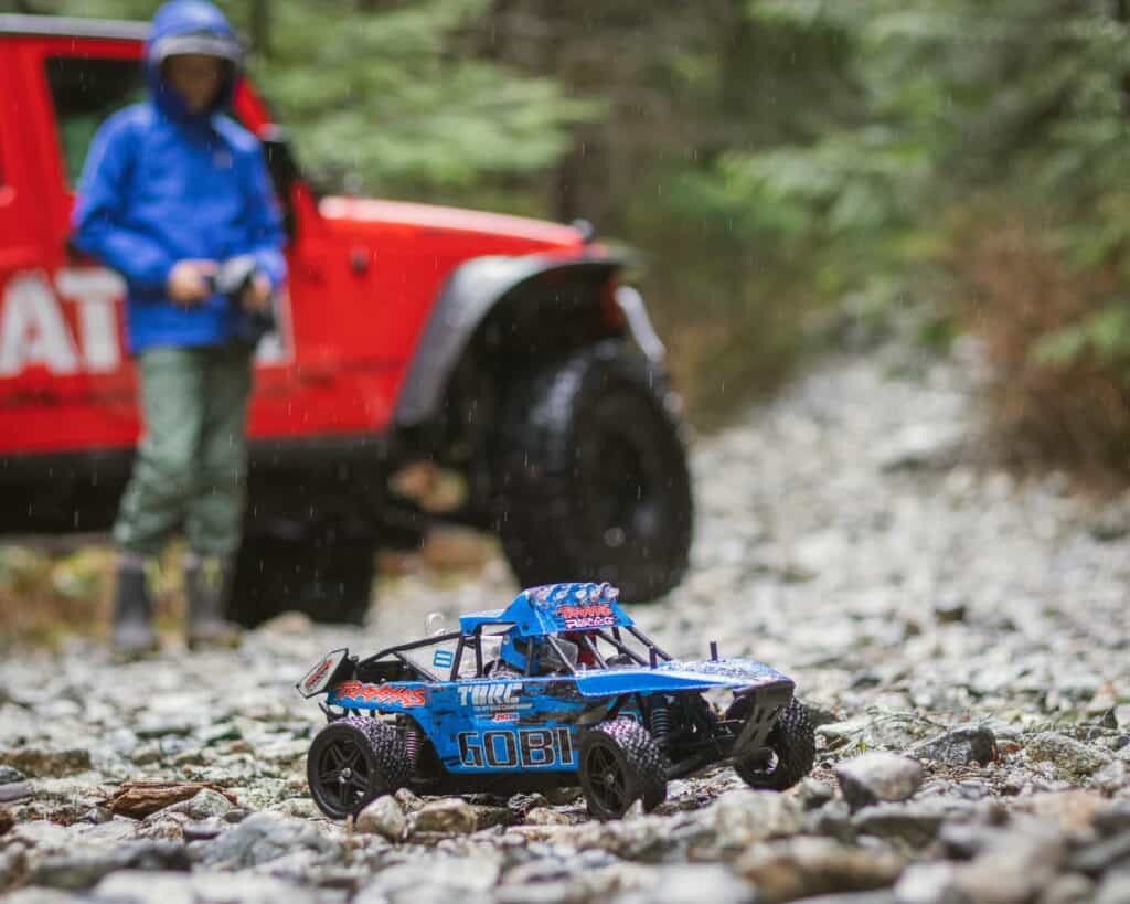 Blue RC car out on rocks with red jeep in background one of many prospecting strategies