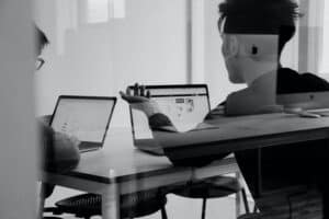 Black and white two guys looking at computers at desk