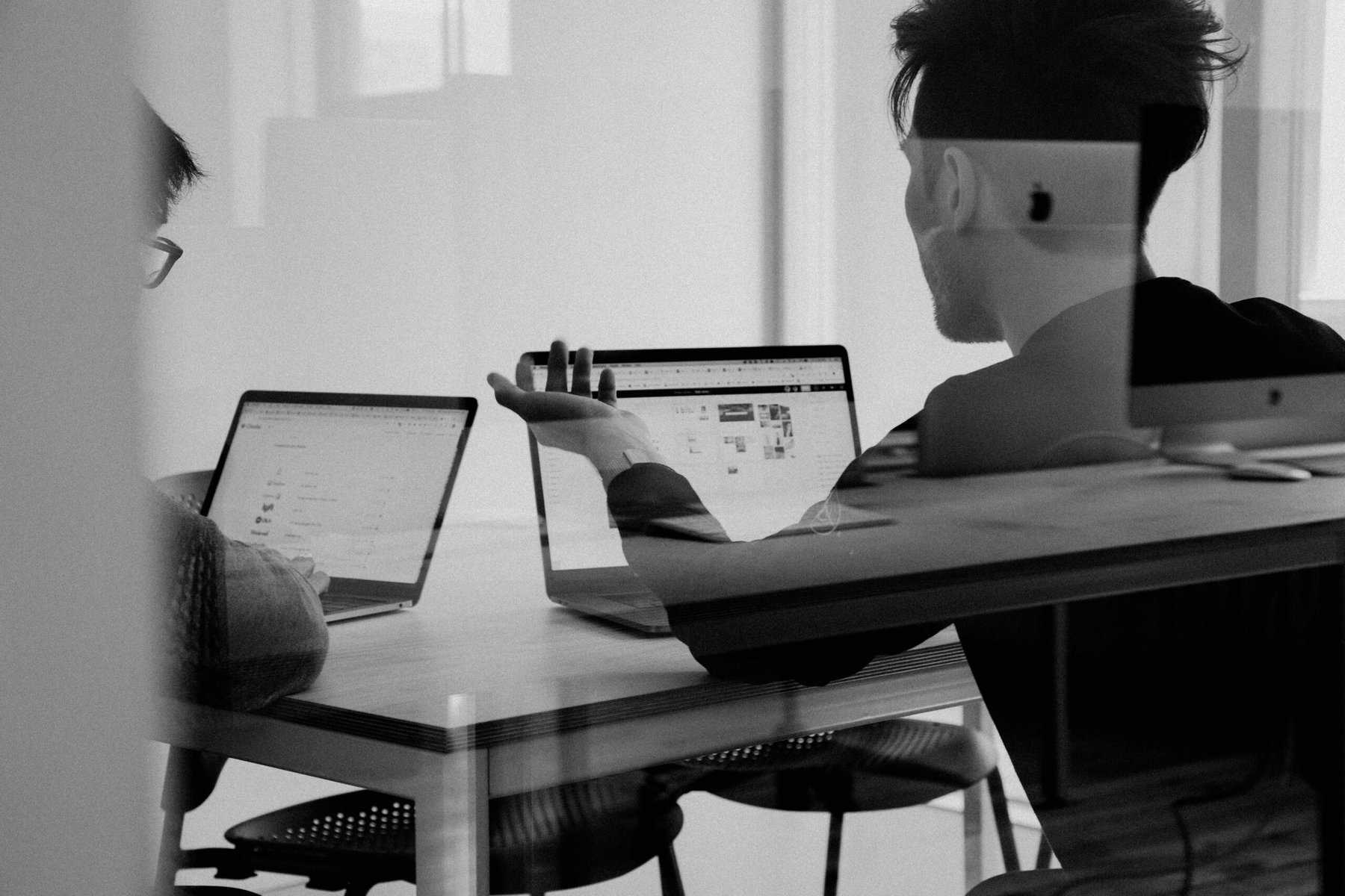 Black and white two guys looking at computers at desk