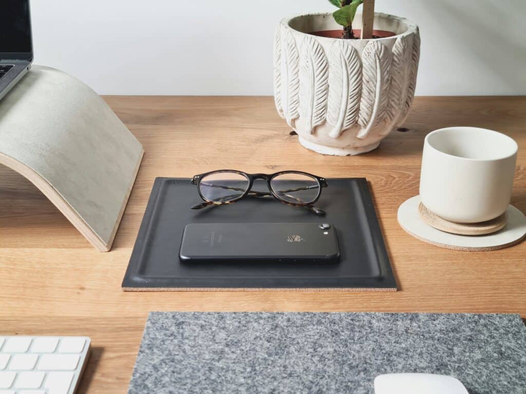 phone, eyeglasses, plant, computer stand on desk