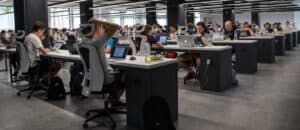 open floor with many desks with workers on computers