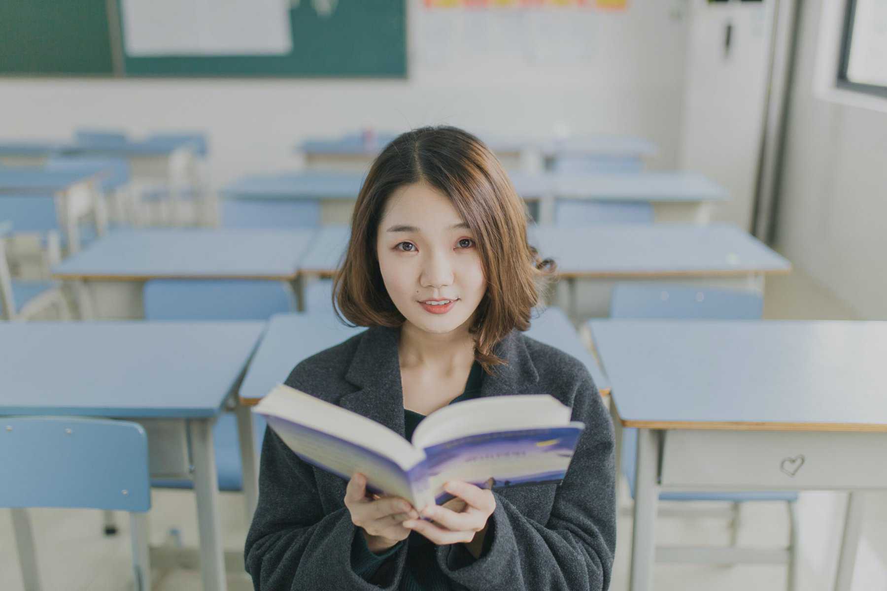 woman reading sales training book in front of rows of desks