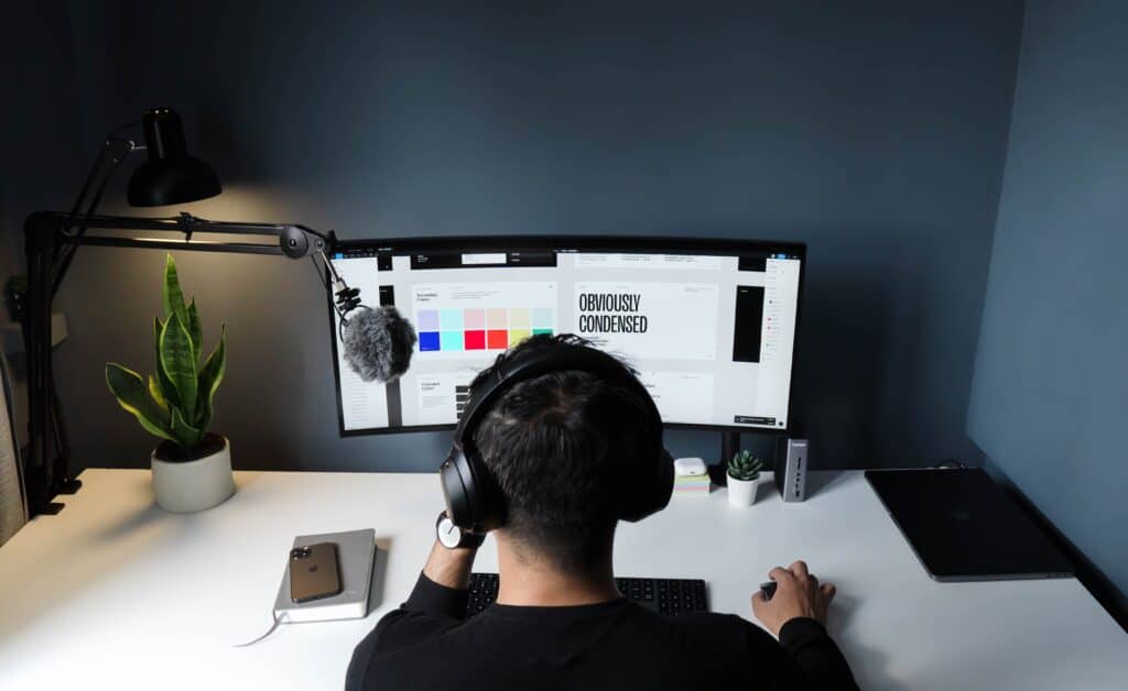 man with headphones at computer working on graphic design also responsible for sales prospecting