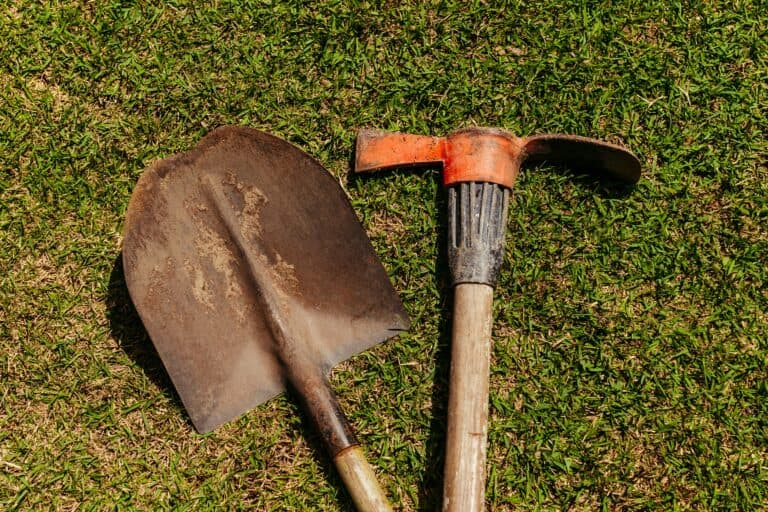 shovel and pickaxe laying in grass