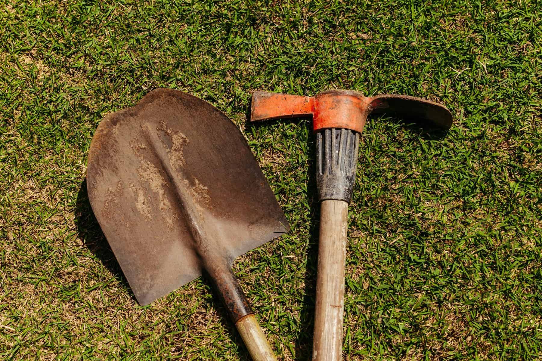 shovel and pickaxe laying in grass