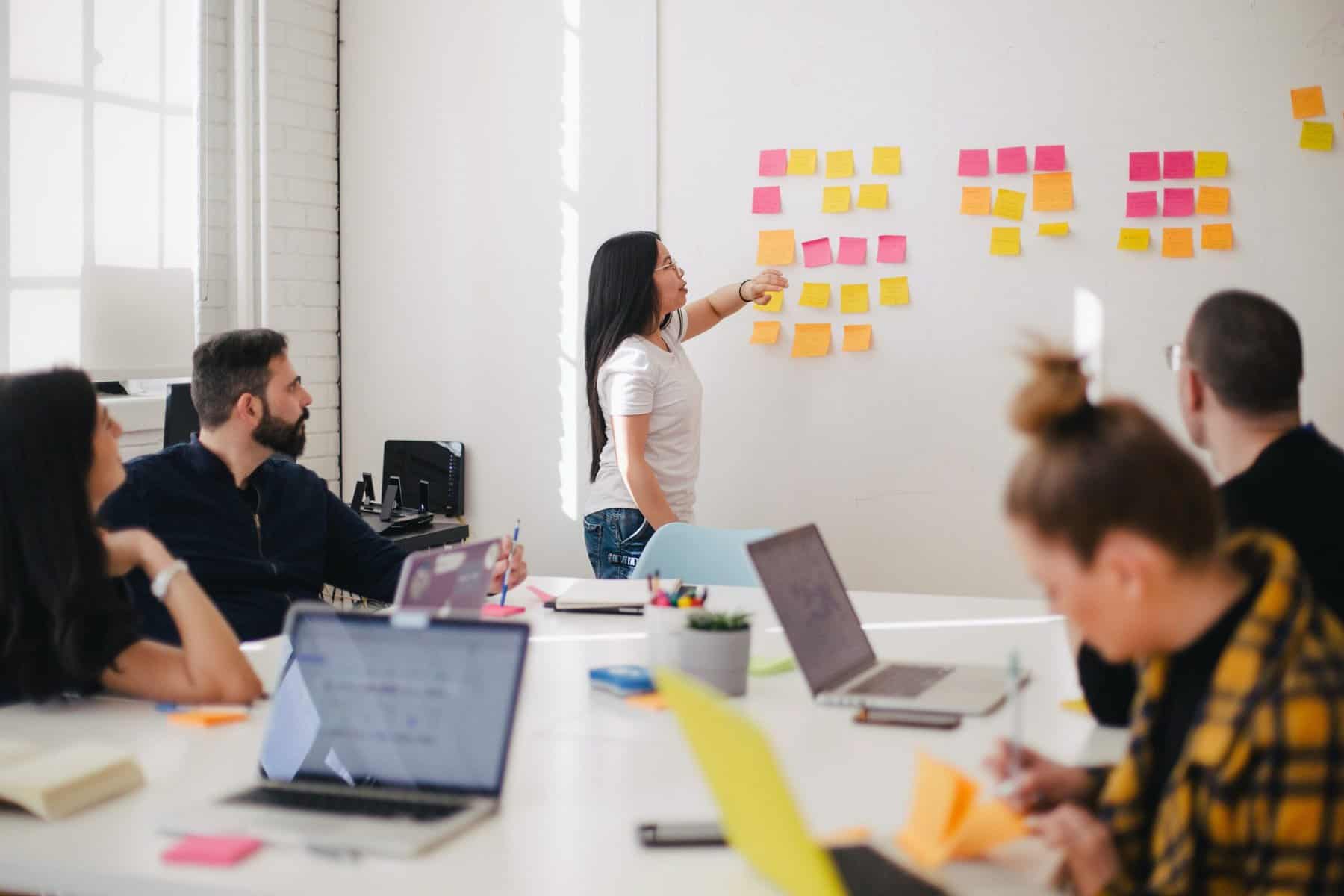 woman putting up sticky notes during a sales training for marketers