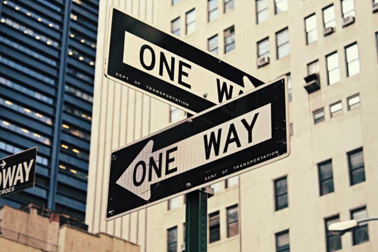 two intersecting black and white one way signs
