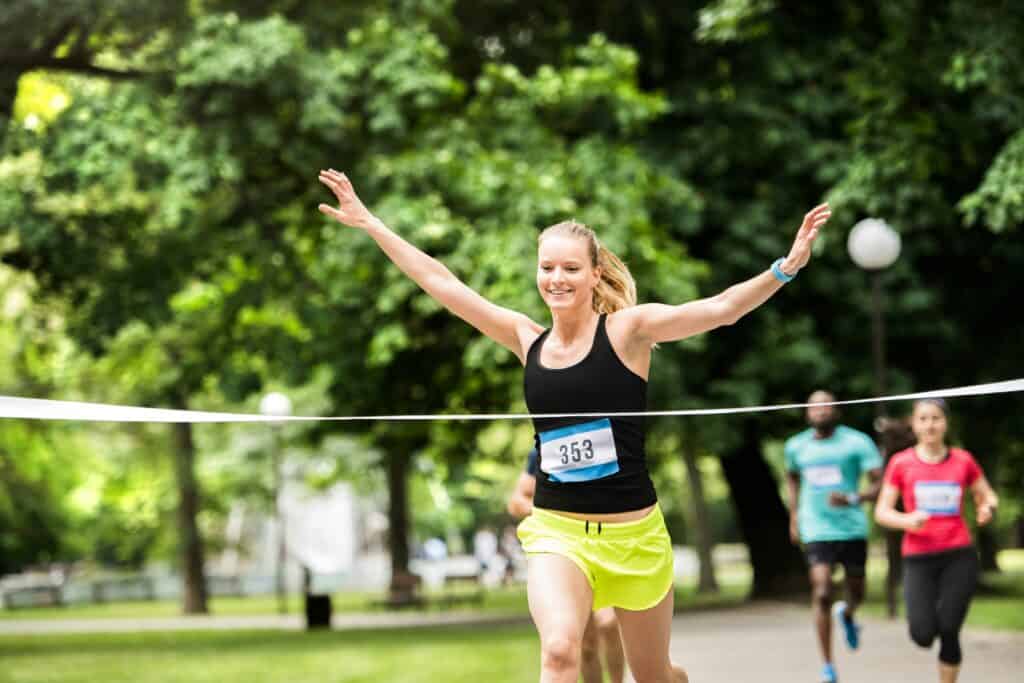 woman with hands up crossing the finish line of a foot race