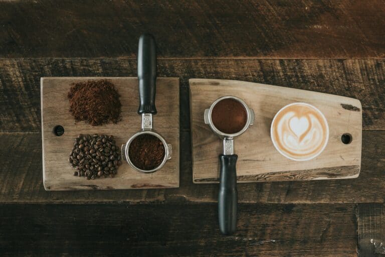 wood boards displaying coffee presses with beans, ground coffee and finished latte