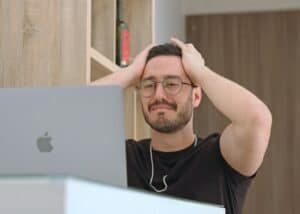 frustrated man holding his head looking at his computer