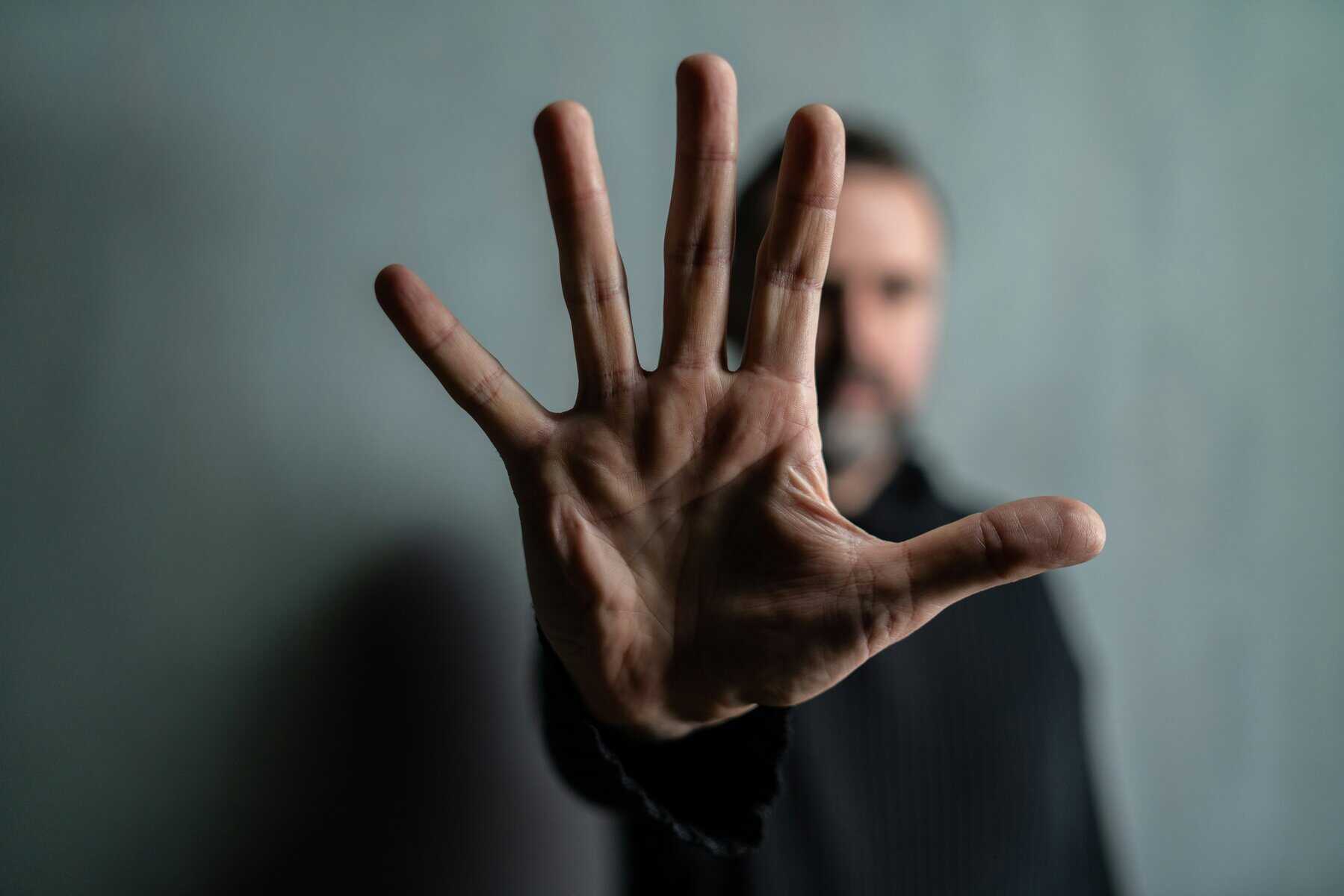 spread out hand signaling stop with blurred man in background