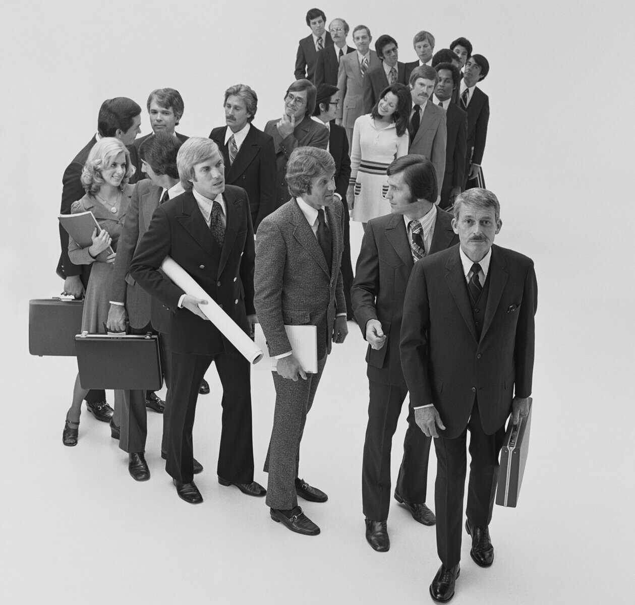 black and white retro 60s photo of professional men and women standing in a curved line
